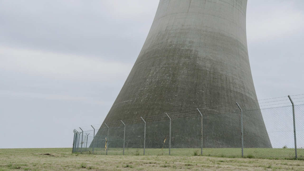 AI-generated editorial image: Modern industrial cooling towers of a nuclear energy generating facility under soft daylight