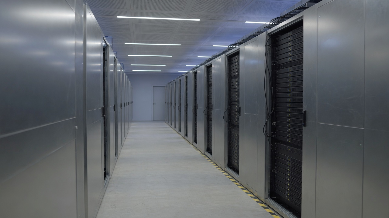 AI-generated editorial image: A quiet modern enterprise data center server aisle with subtle server rack status indicators and soft natural illumination